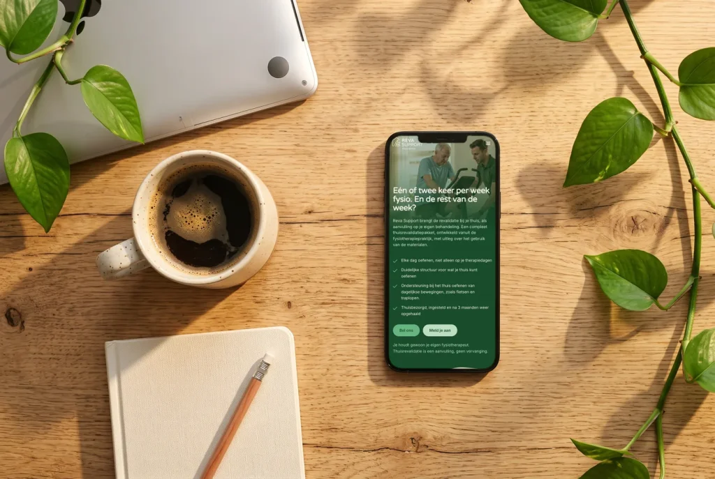 De website van Reva Support op een telefoon, op een houten tafel naast koffie en een notitieboek
